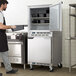 A man standing in front of a Beverage-Air stainless steel undercounter freezer with 6" casters.