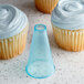 A cupcake with blue frosting and a plastic cone on top.