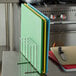 A Vollrath stainless steel cutting board rack holding several colorful cutting boards.