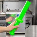 A hand holding a green plastic meat tamper.