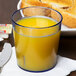 A Cambro slate blue plastic tumbler filled with orange juice on a table next to a plate of toast.