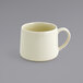 A close up of a Front of the House white porcelain cup with a handle.