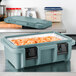 A slate blue Cambro food pan carrier with food inside.