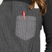 A woman wearing a black and white pinstripe apron with natural webbing and 3 pockets, including a red pen pocket.