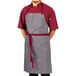 A man wearing a slate gray Uncommon Chef apron with maroon webbing.