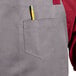 A slate gray Uncommon Chef Rebel bib apron with burgundy webbing and a pencil in the pocket.