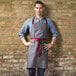 A man wearing a slate gray Uncommon Chef apron with burgundy webbing.