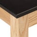 A black National Public Seating science lab table top with wood grain.