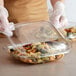 A person in gloves holding a Fineline plastic container with pasta.