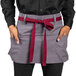 A man wearing a Uncommon Chef slate gray waist apron with burgundy accents.