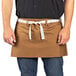 A man wearing a brown Uncommon Chef waist apron with natural webbing.