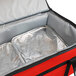 A red and black Sterno food carrier bag with a silver tray inside.