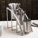 A Cal-Mil steel vertical flatware display with metal containers holding silverware.