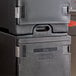 A stack of black Choice front loading insulated food pan carriers on a counter.