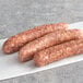 Three Warrington Farm Meats knockwurst sausages on a white surface.