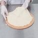 A person making pizza dough on a pizza peel.