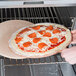 An American Metalcraft pizza peel with a pizza in an oven.