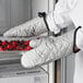 A person wearing San Jamar silicone-coated oven mitts holds a tray of berries.