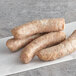 Three Warrington Farm Meats Weisswurst sausages on a white paper.