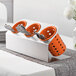 A Steril-Sil stainless steel flatware organizer with orange plastic cylinders holding silverware.