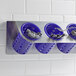 A Steril-Sil stainless steel flatware organizer with purple plastic cylinders holding silverware.