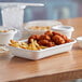 A tray of food with chicken nuggets and fries in a white compostable takeout container.