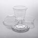 Choice clear plastic cups with 4 oz. inserts and dome and flat lids on a table.