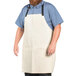 A man with a beard wearing a white Uncommon Chef bib apron with black webbing.