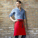 A man wearing a red Uncommon Chef waist apron with black webbing.