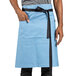 A man in a blue Uncommon Chef waist apron with black straps.