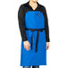 A woman wearing a blue Uncommon Chef bib apron with black webbing.