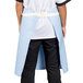 A person wearing a sky blue Uncommon Chef waist apron with natural webbing and 3 pockets.
