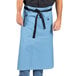 A man wearing a blue Uncommon Chef Muse bistro apron with black webbing.