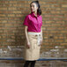 A woman in a pink shirt wearing a light beige Uncommon Chef Moxie waist apron.