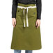 A woman wearing a moss green Uncommon Chef bistro apron with natural webbing.