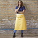 A woman wearing a yellow Uncommon Chef Marvel Bistro apron with natural webbing.
