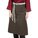 A woman wearing a dark brown Uncommon Chef bistro apron with natural webbing.
