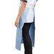 A woman wearing a sky blue Uncommon Chef bistro apron.