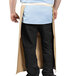 A man in a tan Uncommon Chef bistro apron with natural webbing and one pocket.