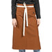 A woman wearing a brown Uncommon Chef Marvel Bistro apron with natural webbing.