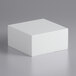A white cube on a gray surface.