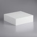 A white square Baker's Mark foam cake dummy on a grey surface.