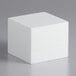 A white Baker's Mark foam square cake dummy cube on a grey surface.