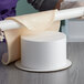 A person using a Baker's Mark foam round cake dummy to roll out dough.