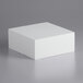 A white square foam cake dummy on a gray surface.