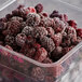 A plastic container filled with frozen boysenberries.