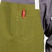 A person wearing a moss green Uncommon Chef bib apron with natural webbing.