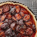 A close up of a tart made with halved plums on a cooling rack.