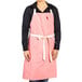 A woman wearing a coral pink Uncommon Chef apron.