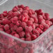 A plastic container of frozen red raspberries.